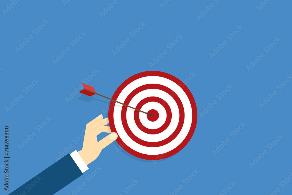 Hand holding a target, showing a goal. Red arrow hits the center. Business challenge failure and success concept. Hand holding a target, showing a goal. Red arrow hits the center. Business challenge failure and success concept.