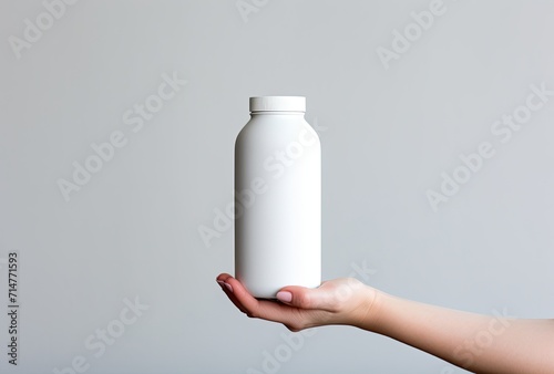 A mockup featuring a woman's hand holding a cosmetic beauty product container with a blank white plastic surface, ready for branding or product presentation.