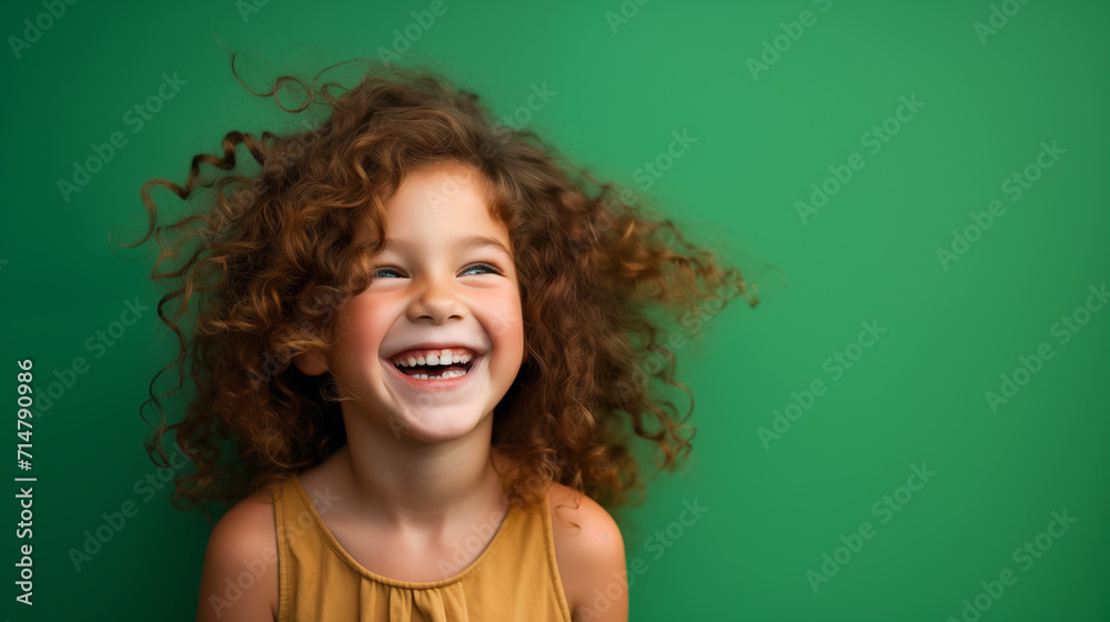 Obraz na płótnie Portret studyjny dziewczynki uśmiechniętej na zielonym tle z dużą ilością wolnego tła w salonie