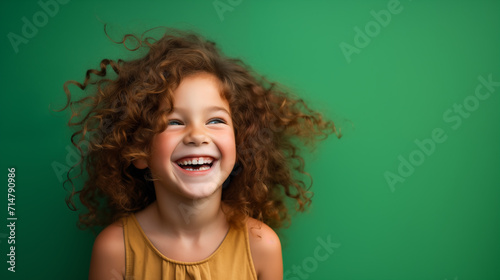 Portret studyjny dziewczynki uśmiechniętej na zielonym tle z dużą ilością wolnego tła photo