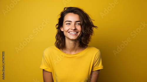 Portret studyjny młodej kobiety uśmiechniętej na żółtym tle z dużą ilością wolnego tła photo