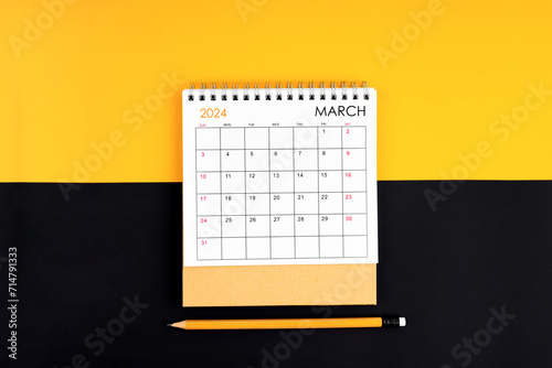 Top view of March 2024 desk calendar and pencil on yellow and black.