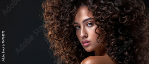 Ethereal beauty: a woman's piercing gaze amidst a cascade of rich, curly locks—intensity wrapped in softness