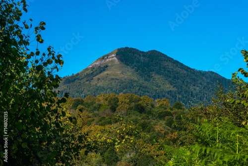 mountain with two peaks overgrown with green forest and small rocky scree in the Western Caucasus (South Russia)