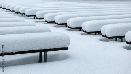 Fotografering wooden benches covered with a thick blanket of snow, play of light and shadows,