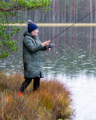 fisherwoman on the shore of a swamp lake, forest and swamp vegetation, rainy and cloudy day