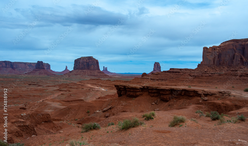 Desert landscape with red rocks and dry vegetation on red sands in Monument Valley, Navajo Nation,  Arizona - Utah