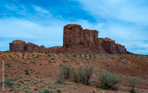 Desert landscape with red rocks and dry vegetation on red sands in Monument Valley, Navajo Nation, Arizona - Utah