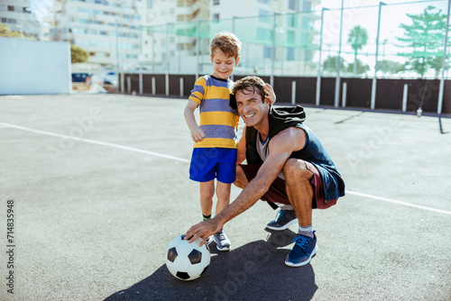 Father and son playing football outdoors at the local court