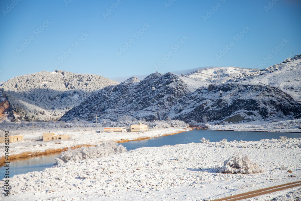 Snow. Winter landscape covered in a white blanket of snow covering mountains and roads. Trees with snow. Clear day. White blanket due to a storm with heavy snowfall. In Spain. January. 2024.