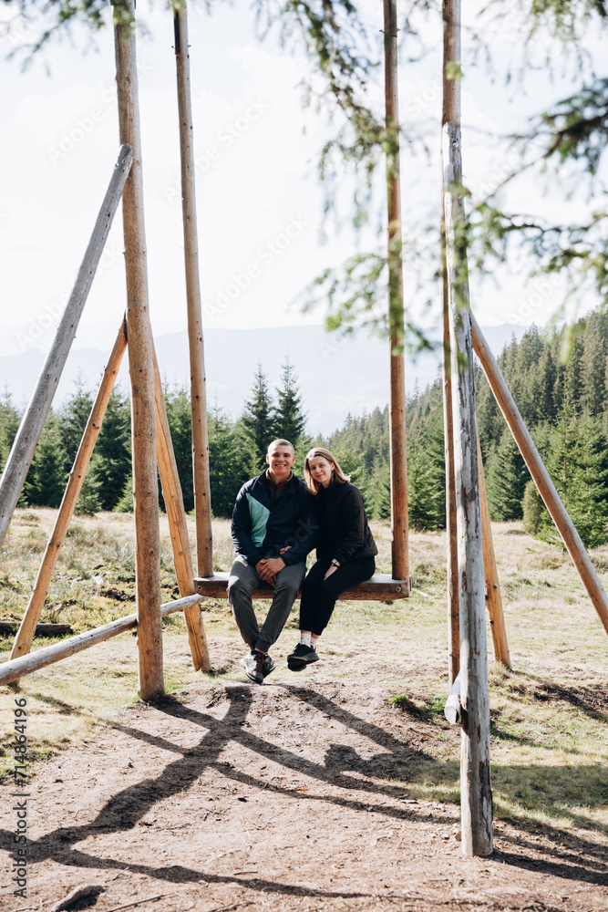 a man and a woman are traveling in the mountains. a couple sits on a large wooden swing high in the mountains. autumn in the mountains
a man and a woman are traveling in the mountains. a couple sits on a large wooden swing high in the mountains. autumn in the mountains