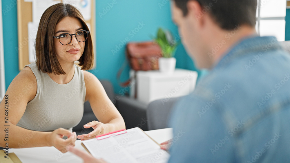 Fototapeta premium Two workers man and woman reading document sitting on table at the office