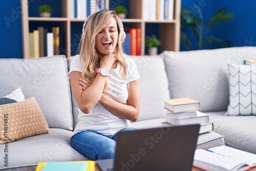 Young blonde woman studying using computer laptop at home shouting suffocate because painful strangle. health problem. asphyxiate and suicide concept.