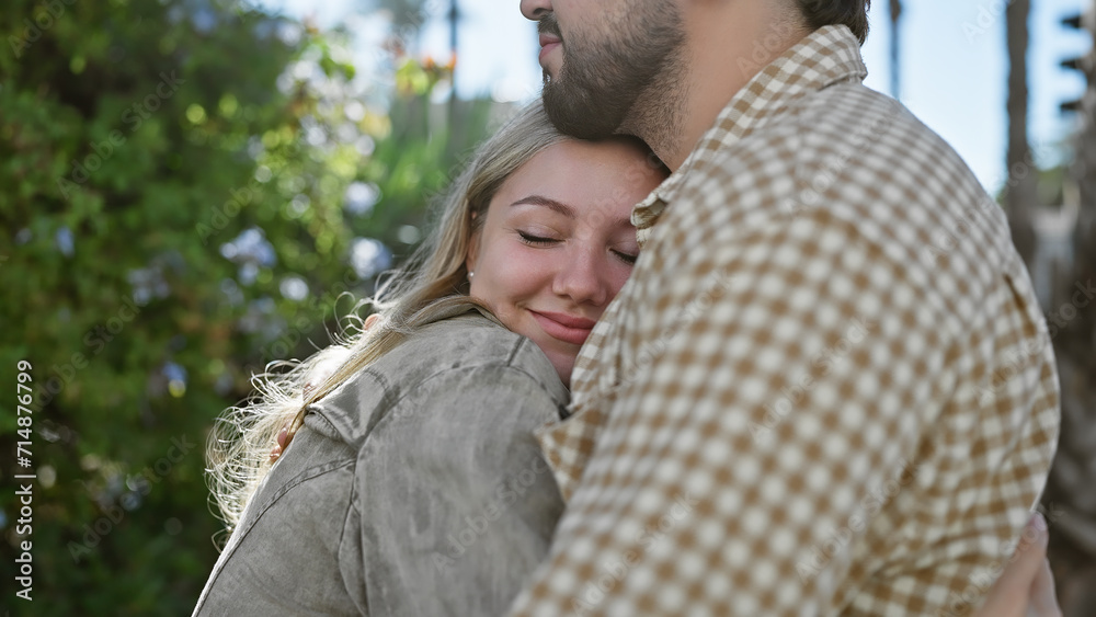 A content woman embraces a man outdoors, surrounded by nature and sunlight. A content woman embraces a man outdoors, surrounded by nature and sunlight.