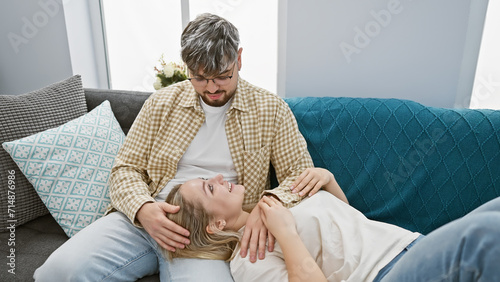 A contented couple relaxes in a cozy living room, sharing an intimate and joyful moment together on a plush couch.