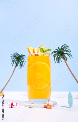 Glass of 100% Orange juice with orange slices fruits on sea beach with white sand. Summer sea vacation and travel concept. Exotic summer drinks. © NaMong Productions