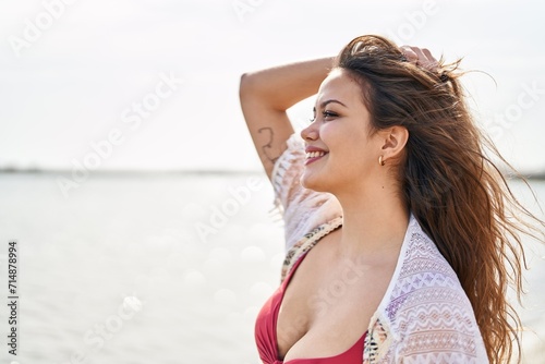 Young beautiful hispanic woman tourist smiling confident wearing bikini at beach