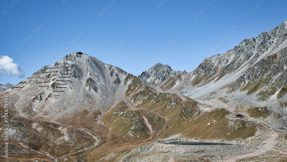 Alpine Berge, Stausee, Wasserspeicher. Geröll und felsige Hänge, Hochalpines Gelände. Blauer Himmel