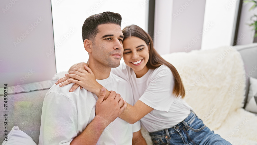 Affectionate woman hugging smiling man from behind on a cozy sofa in a modern living room Affectionate woman hugging smiling man from behind on a cozy sofa in a modern living room