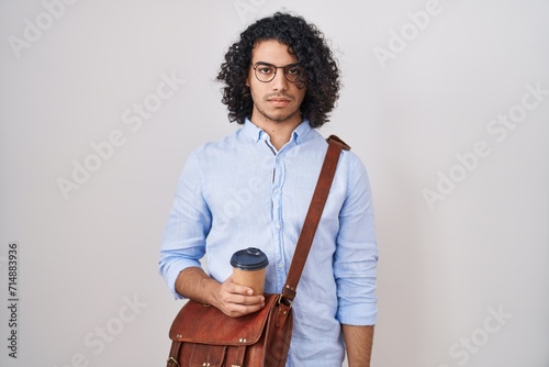 Hispanic man with curly hair drinking a cup of take away coffee skeptic and nervous, frowning upset because of problem. negative person.