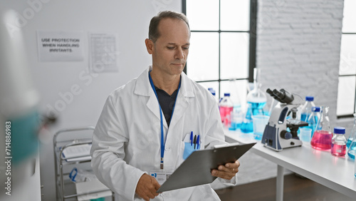 Middle age man  a dedicated scientist  engrossed in reading medical report with a serious expression at his research lab