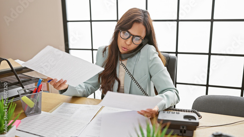 Принти на полотні Stunning young hispanic woman, an emotive employee, engrossed in reading busines