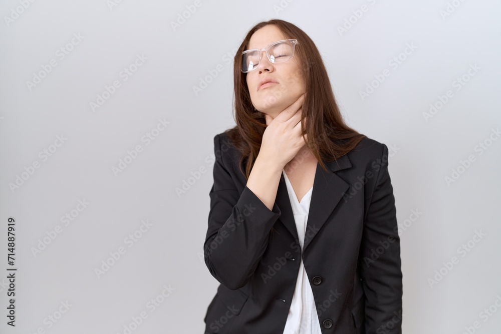 Beautiful brunette woman wearing business jacket and glasses touching painful neck, sore throat for flu, clod and infection Beautiful brunette woman wearing business jacket and glasses touching painful neck, sore throat for flu, clod and infection