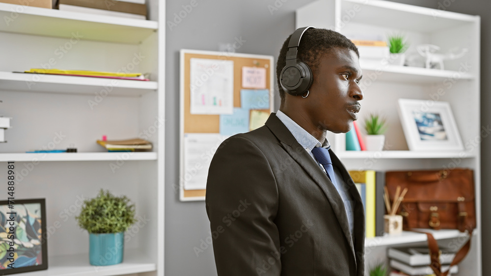 African american man wearing headset in modern office setting listening attentively during a workday. African american man wearing headset in modern office setting listening attentively during a workday.