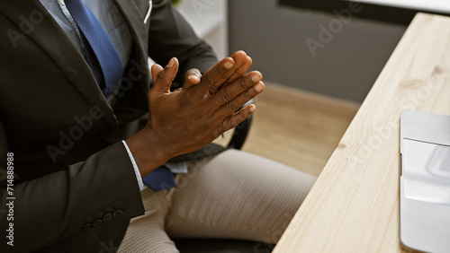 African american man in a suit gestures with his hands at an office setting  showing professionalism and confidence.