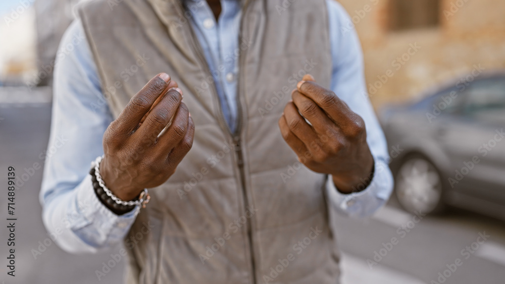 Fototapeta premium African american man in a vest gesturing outdoors in an urban street setting.