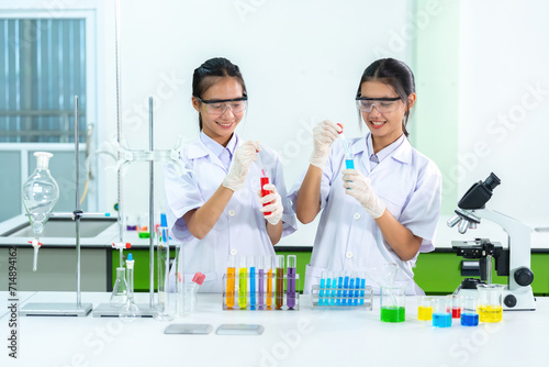 2 Asian female scientists are doctors Drops of solution in vaccine production test tube with microscope in biology lab Used to treat the Covid virus and other epidemics for patients in the world.