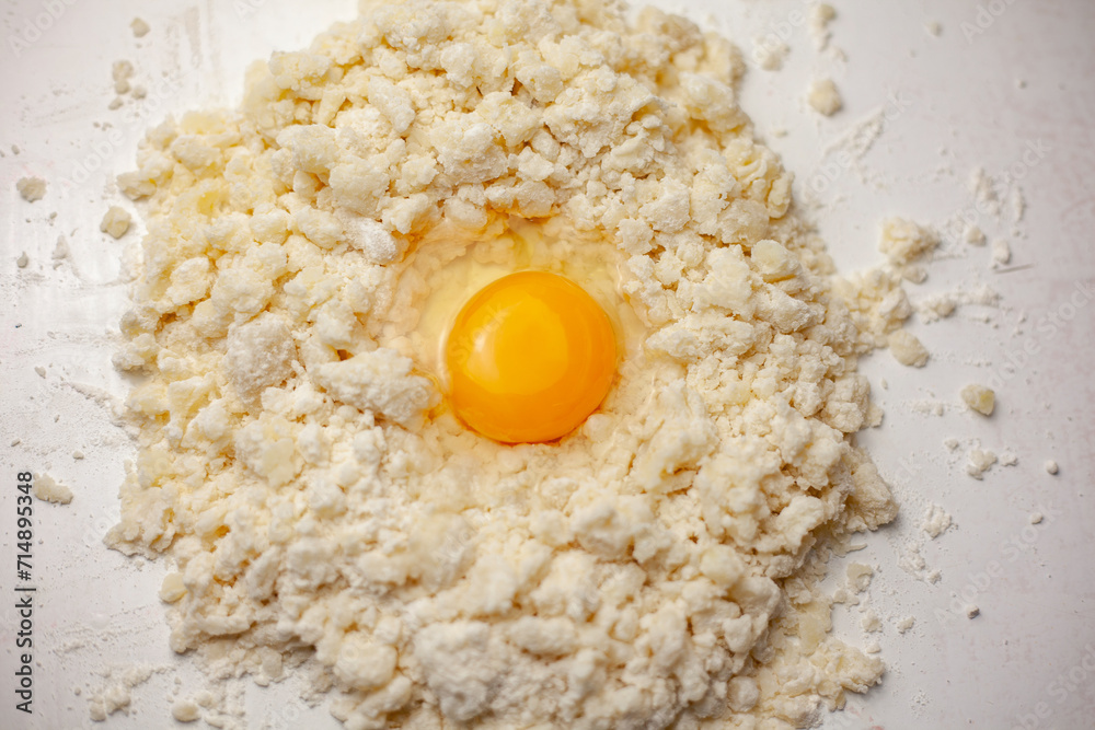 The process of preparing fresh pasta. Cozy kitchen atmosphere. Fresh flour into which an egg has been carefully broken. Top view The process of preparing fresh pasta. Cozy kitchen atmosphere. Fresh flour into which an egg has been carefully broken. Top view