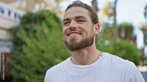 Young hispanic man smiling confident looking to the side at park