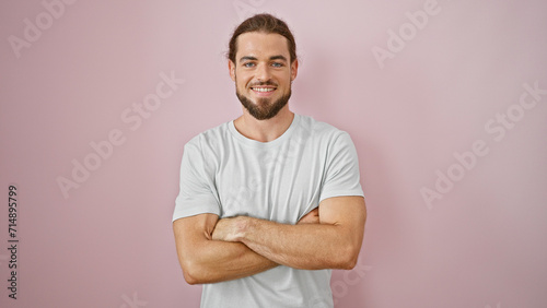Young hispanic man standing with crossed arms smiling over isolated pink background