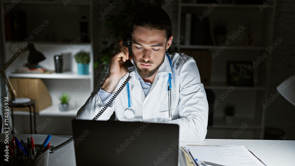 Young hispanic man doctor using laptop talking on telephone at the clinic Young hispanic man doctor using laptop talking on telephone at the clinic