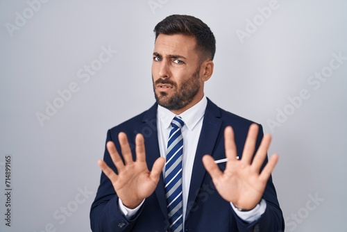Fotografia Handsome hispanic man wearing suit and tie moving away hands palms showing refusal and denial with afraid and disgusting expression