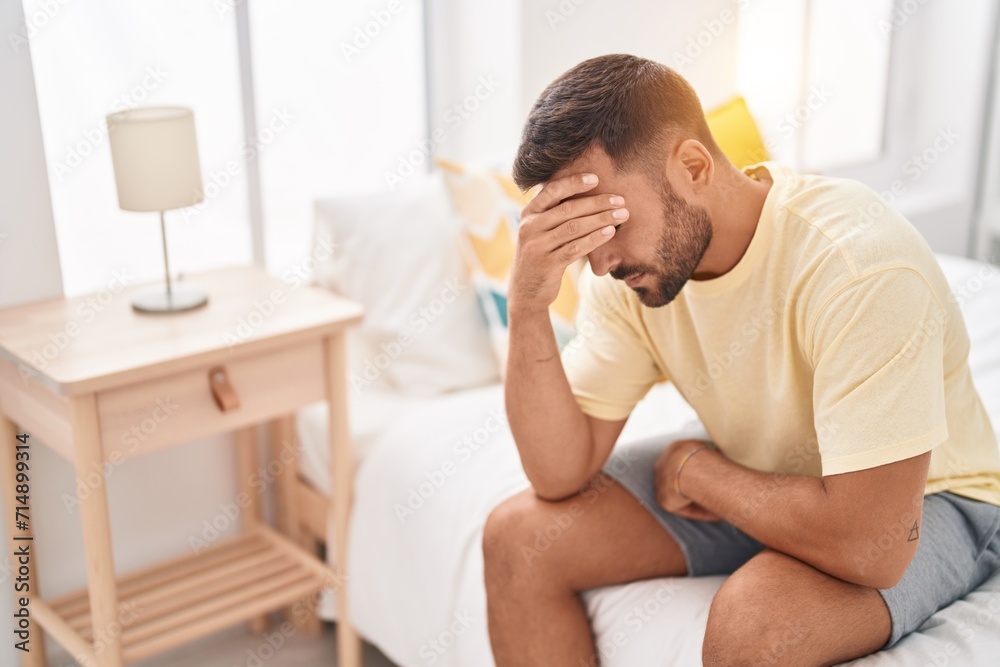 Young hispanic man stressed sitting on bed at bedroom Young hispanic man stressed sitting on bed at bedroom