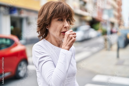 Middle age woman coughing at street