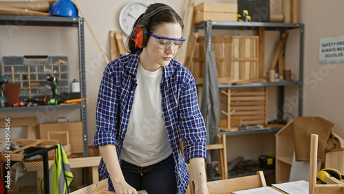 Caucasian woman working attentively in a carpentry workshop with safety equipment