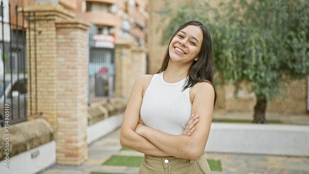 Young beautiful hispanic woman smiling confident standing with arms crossed gesture at park