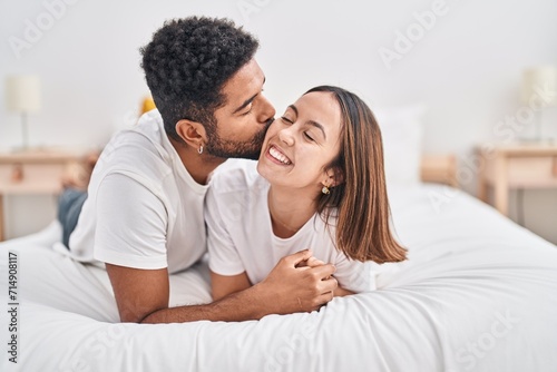 Man and woman couple lying on bed kissing at bedroom