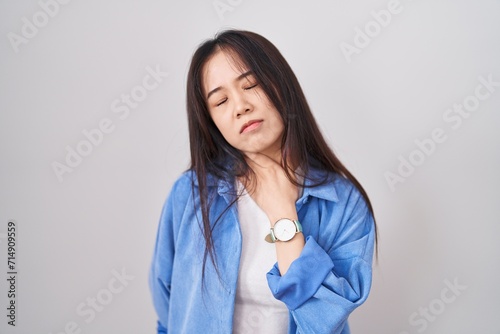 Young chinese woman standing over white background touching painful neck  sore throat for flu  clod and infection