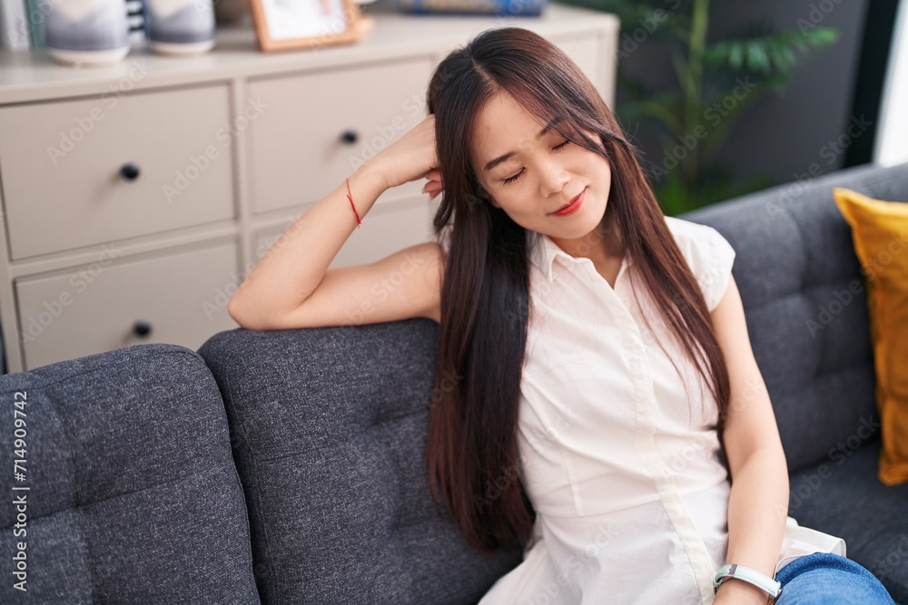 Young chinese woman relaxed with hands on head sitting on sofa at home Young chinese woman relaxed with hands on head sitting on sofa at home