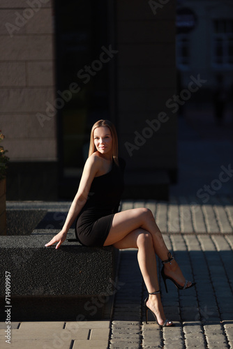 beautiful young woman in a black dress on a walk in summer