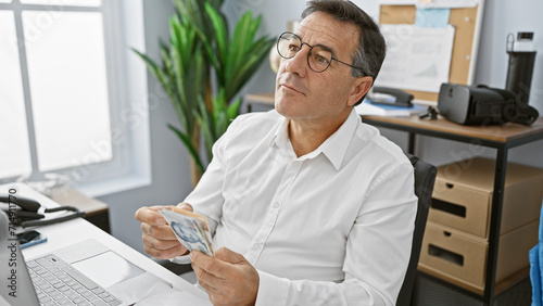 Canvas Print A mature man counts singapore dollars at his office, showing a financial scene full of concentration and professionalism