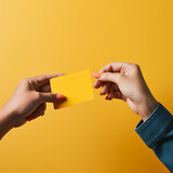 Hand giving a credit card to another hand on a yellow background.