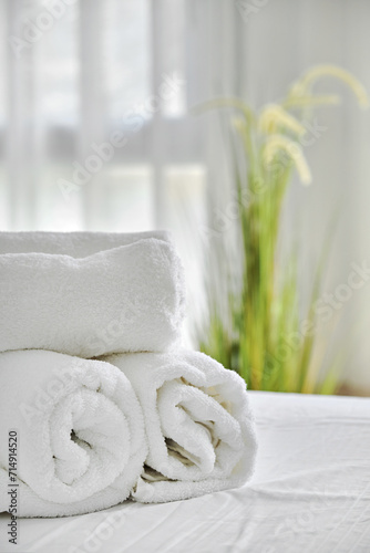 Three folded white towels on bed in cozy bedroom