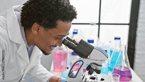 Smiling man using a microscope in a modern laboratory