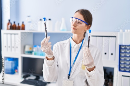 Young caucasian woman scientist holding test tubes at laboratory