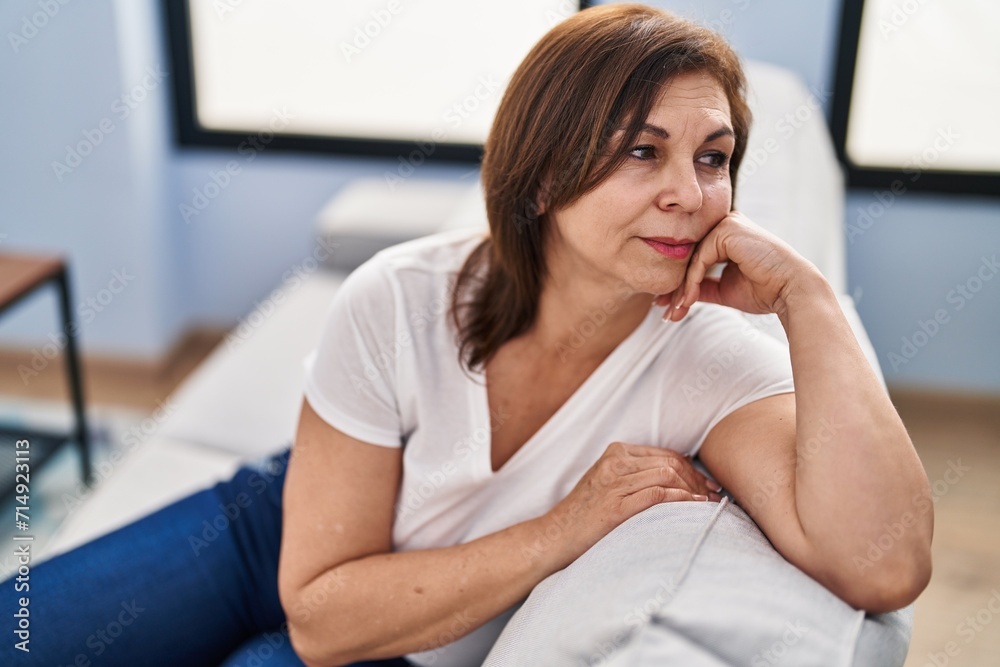 Middle age woman sitting on sofa with serious expression at home Middle age woman sitting on sofa with serious expression at home